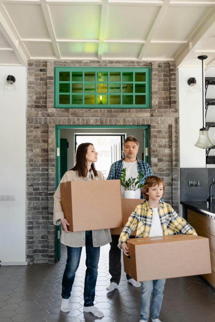A family carrying boxes as they move into their new home, symbolizing new beginnings.
